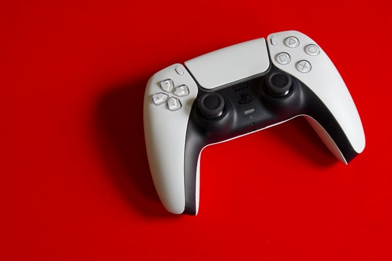 White DualSense controller for PlayStation 5 on a striking red backdrop, emphasizing modern gaming technology.